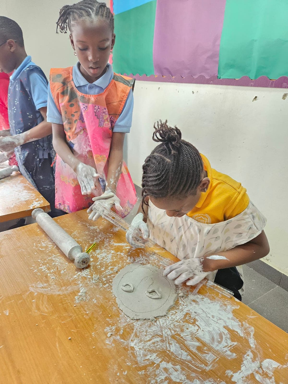 Pupils rolling and shaping clay together at the craft table