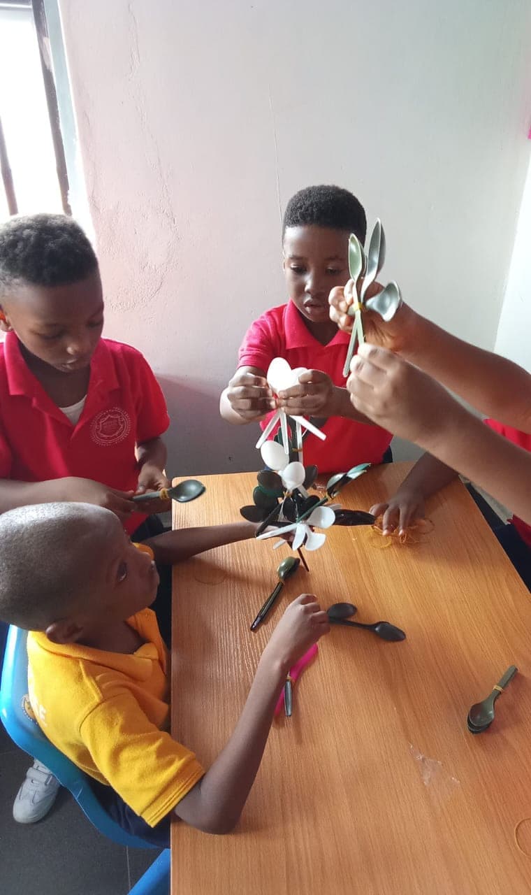 Pupils cutting and folding paper feathers for their peacock model