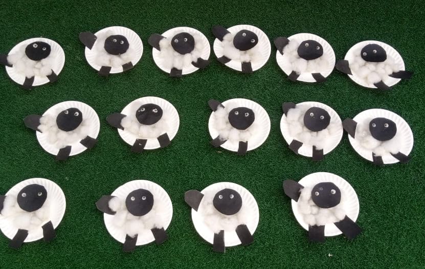 A row of paper-plate sheep made by the nursery class, laid out to dry