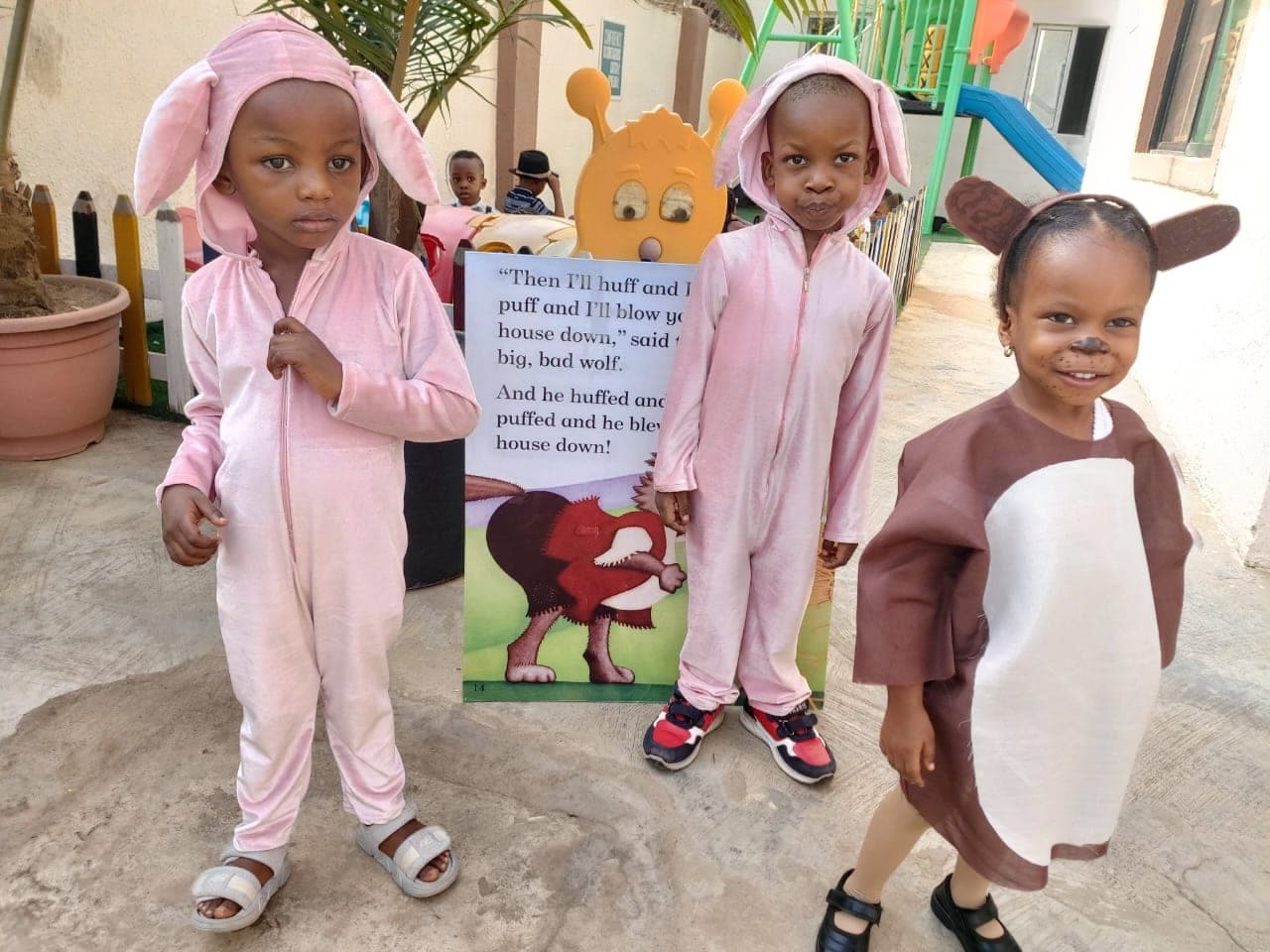 Nursery children dressed as storybook animals beside the reading display