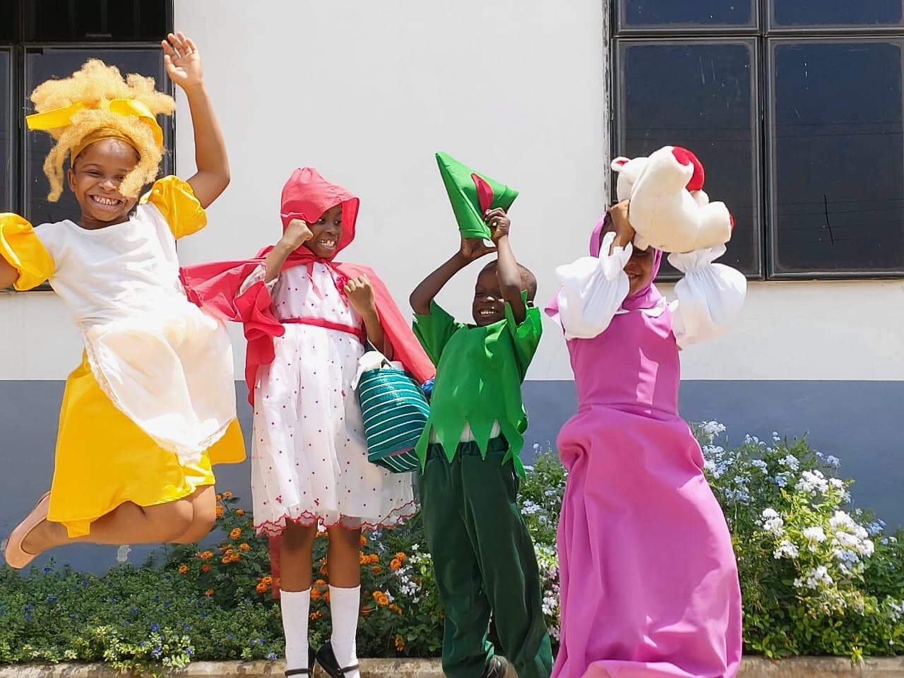 Four pupils caught mid-leap in their World Book Day costumes
