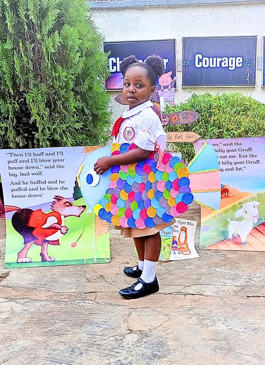 A pupil in costume posing beside the giant storybook display