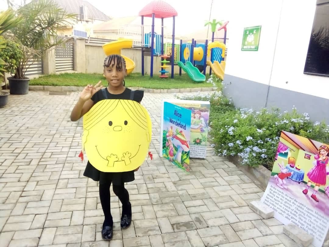 A pupil holding up her sunshine mask beside the World Book Day display