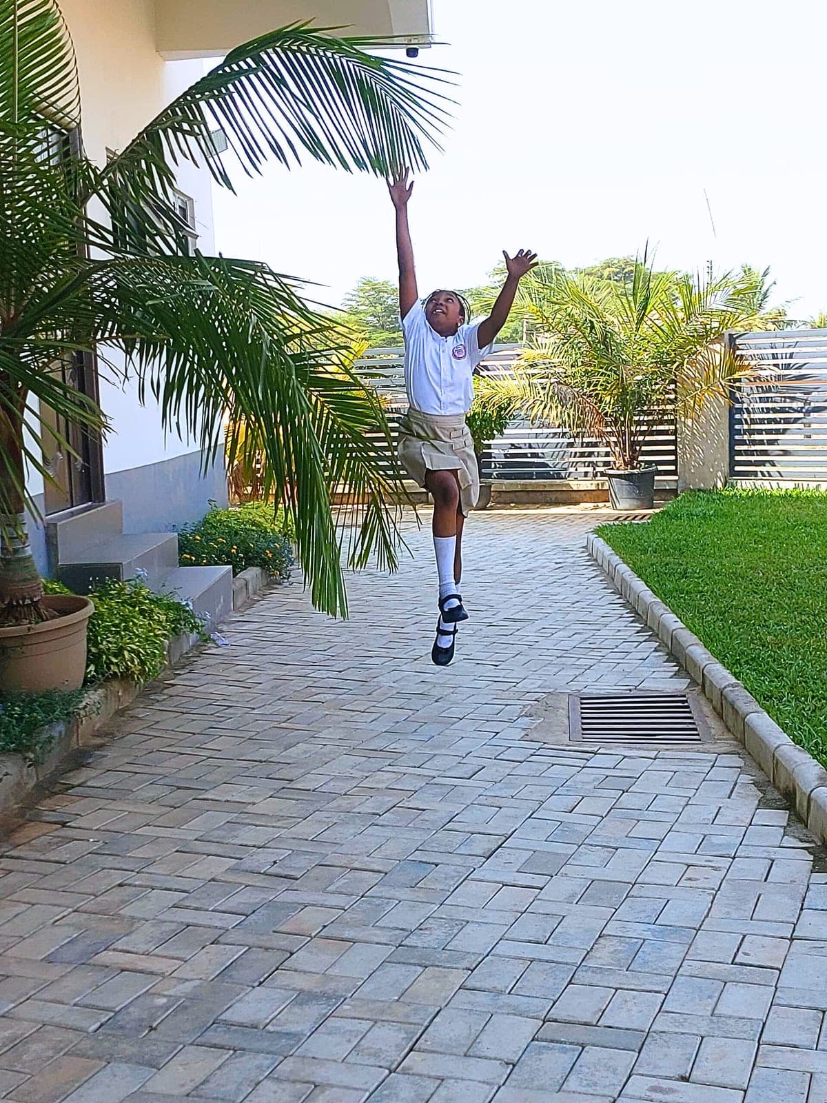 A pupil leaping for joy on the walkway outside school