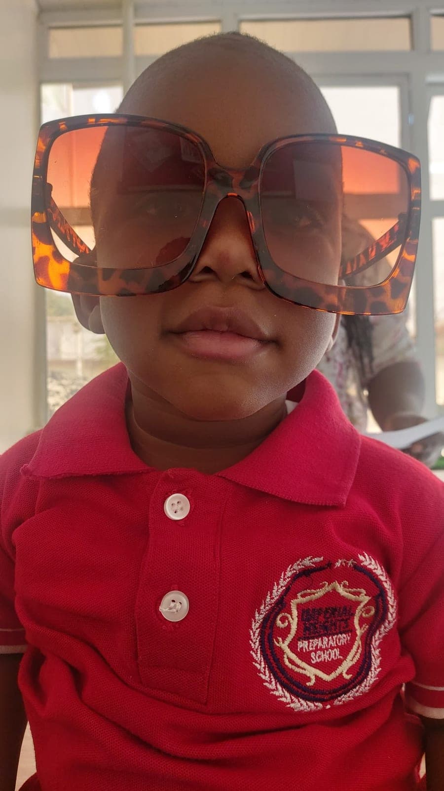 A small pupil peering out from behind oversized sunglasses