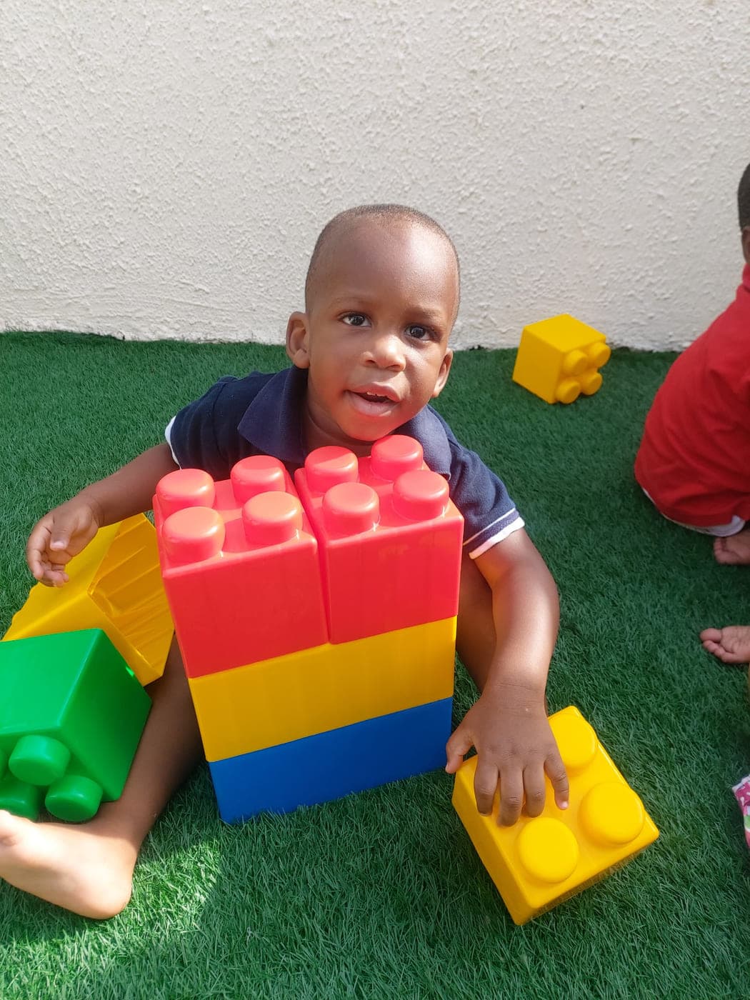 A little boy fitting together the giant building blocks out on the turf