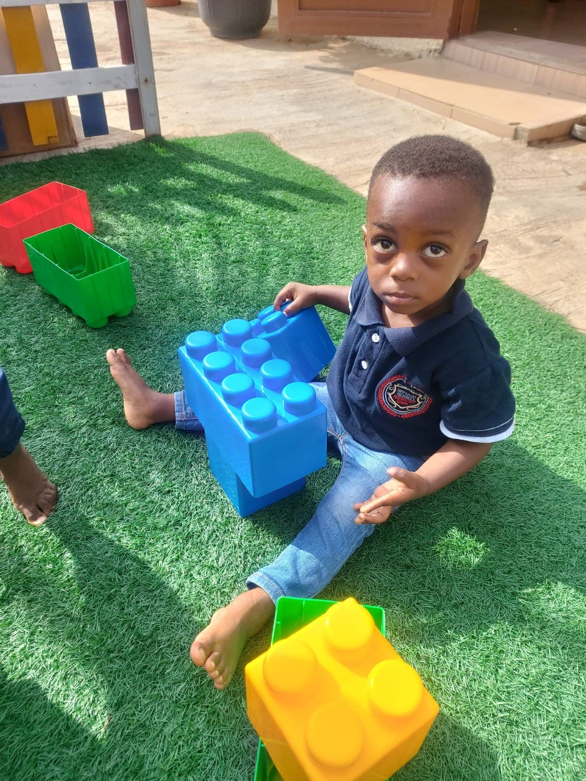 A little boy fitting building blocks together on the turf