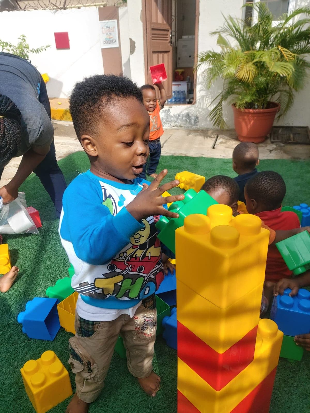 A toddler stacking large building blocks into a tower