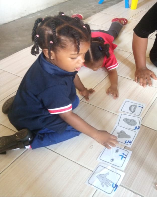 A toddler laying out picture cards on the classroom floor
