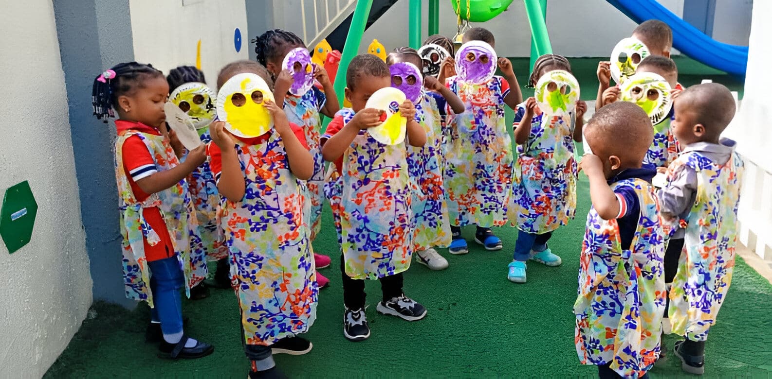 Nursery children in patterned art smocks gathered under the balloons