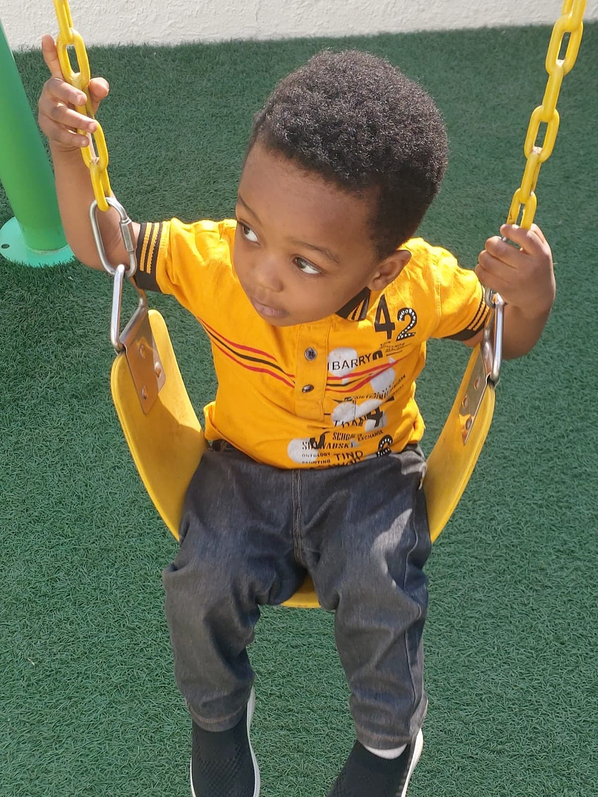 A toddler swinging happily in the baby swing