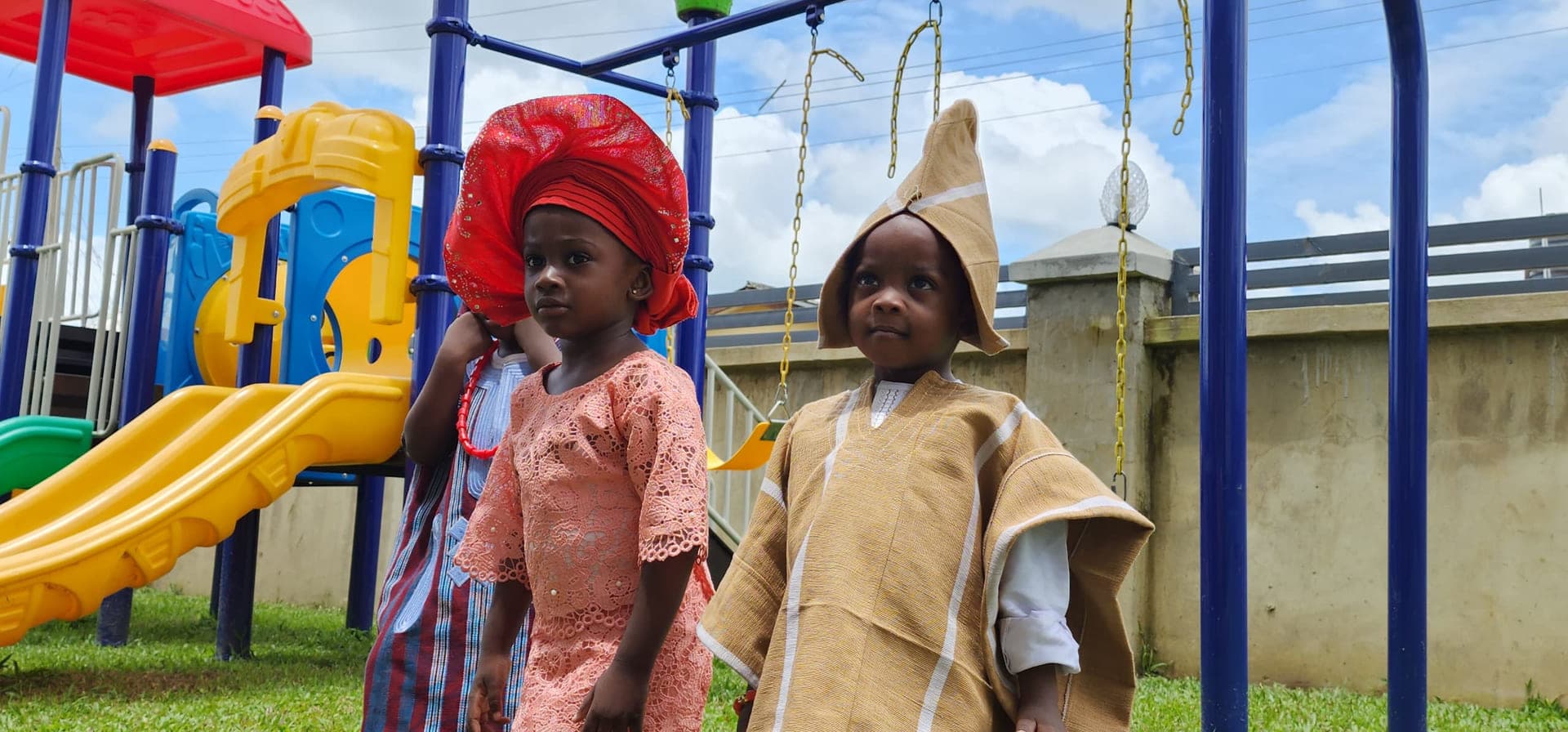 Two pupils in traditional dress beside the playground on Cultural Day