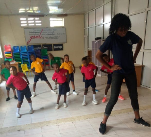 A dance lesson in the school hall, pupils following their teacher
