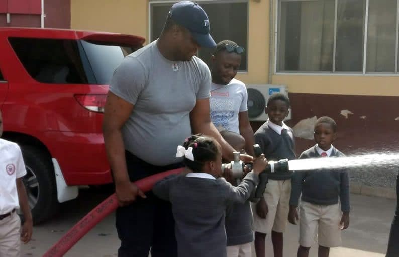 A firefighter showing pupils how the hose works