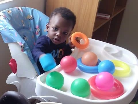 A baby exploring a ball toy in the crèche