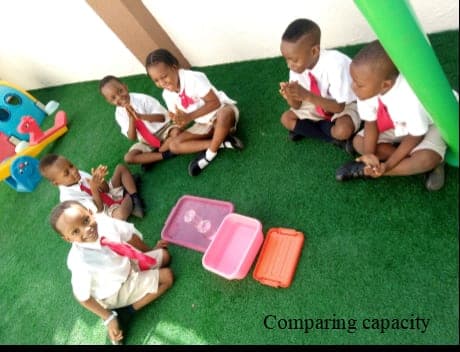 Children comparing the capacity of different containers during an outdoor maths lesson