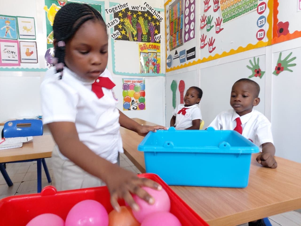 A young pupil sorting coloured balls into a tray in a brightly decorated classroom