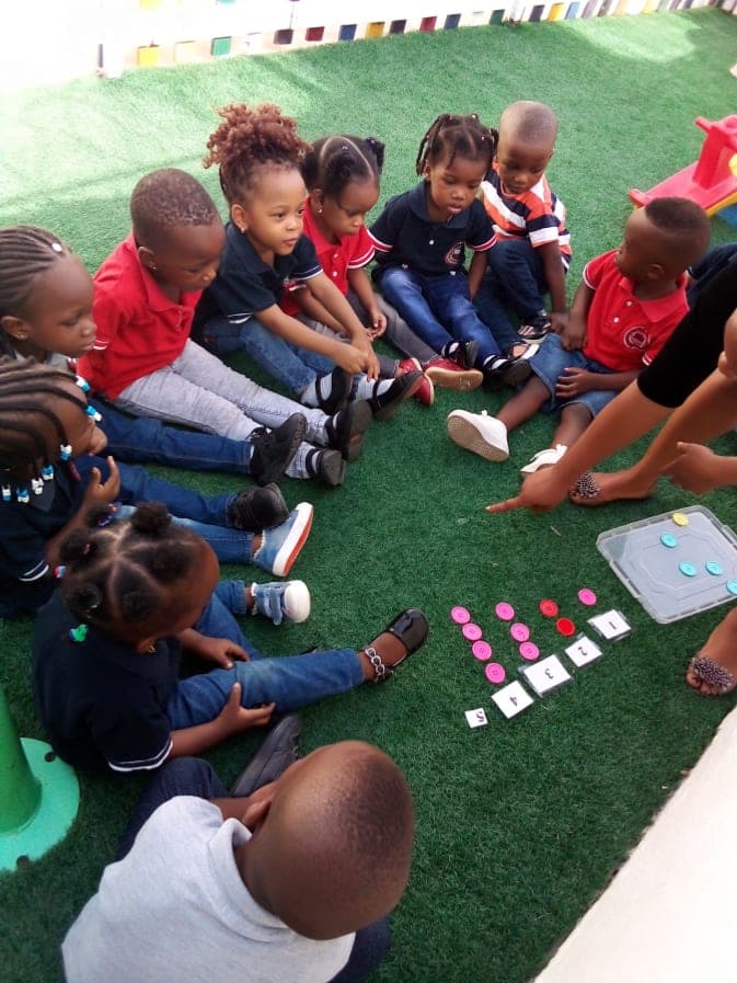 Pupils sitting in a circle on the turf for a picture-card lesson