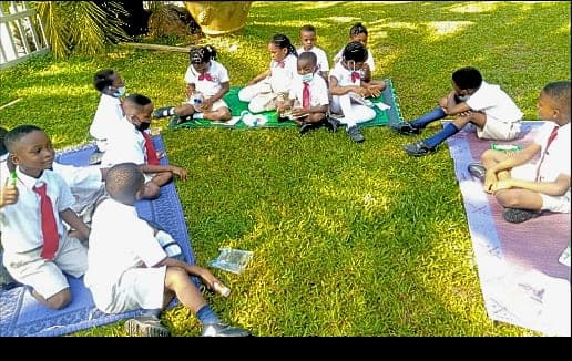 A class reading together on picnic mats spread across the school lawn