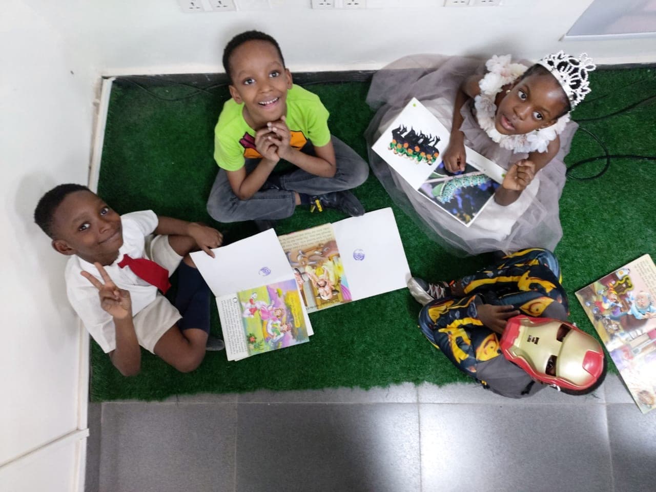 Three children lying on the floor absorbed in their picture books, seen from above