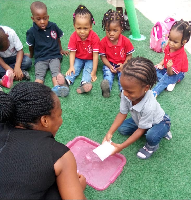 A teacher leading a water-and-sand tray investigation with her class outdoors