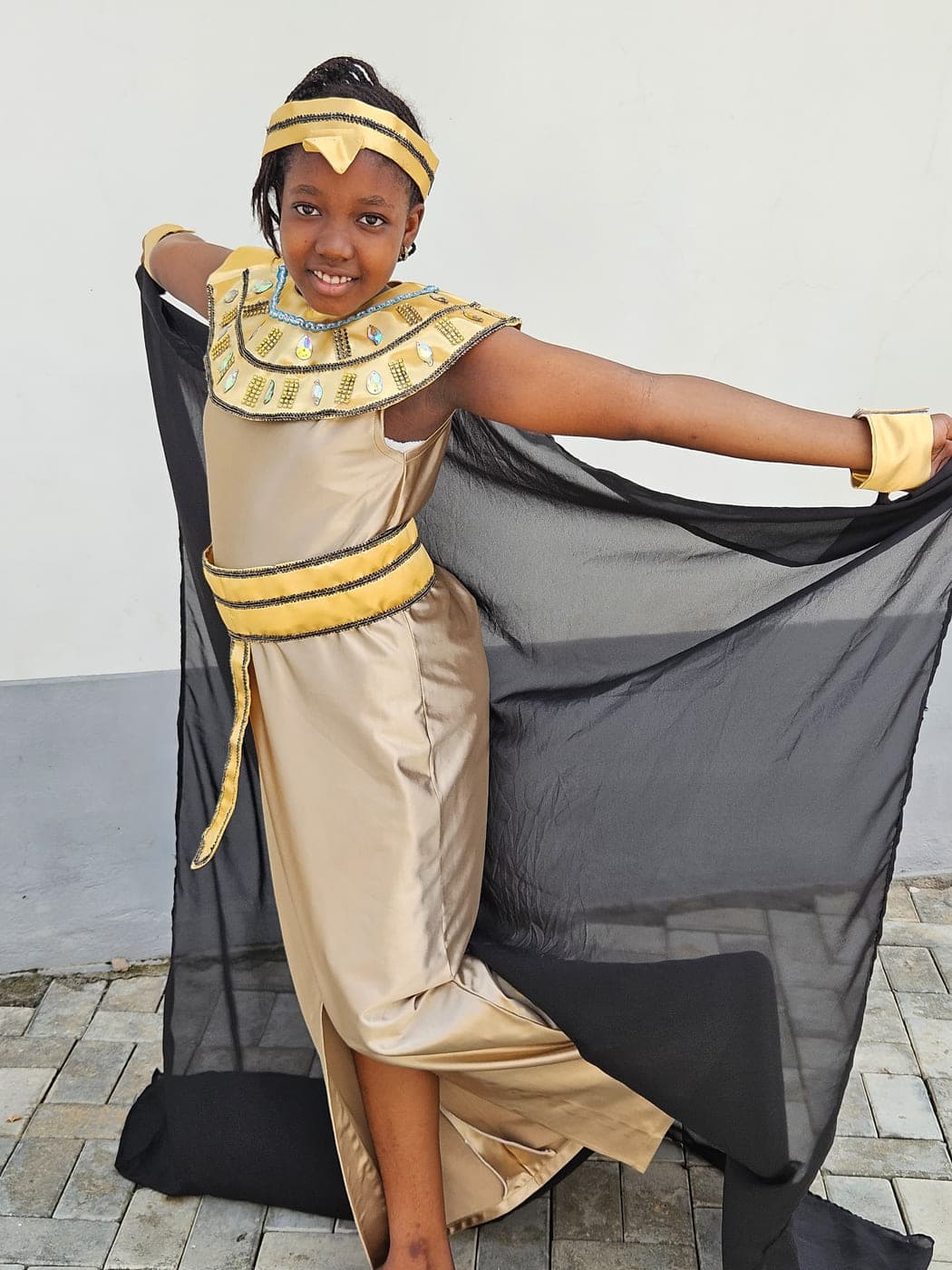 A pupil sweeping out the cape of her Egyptian costume before the performance