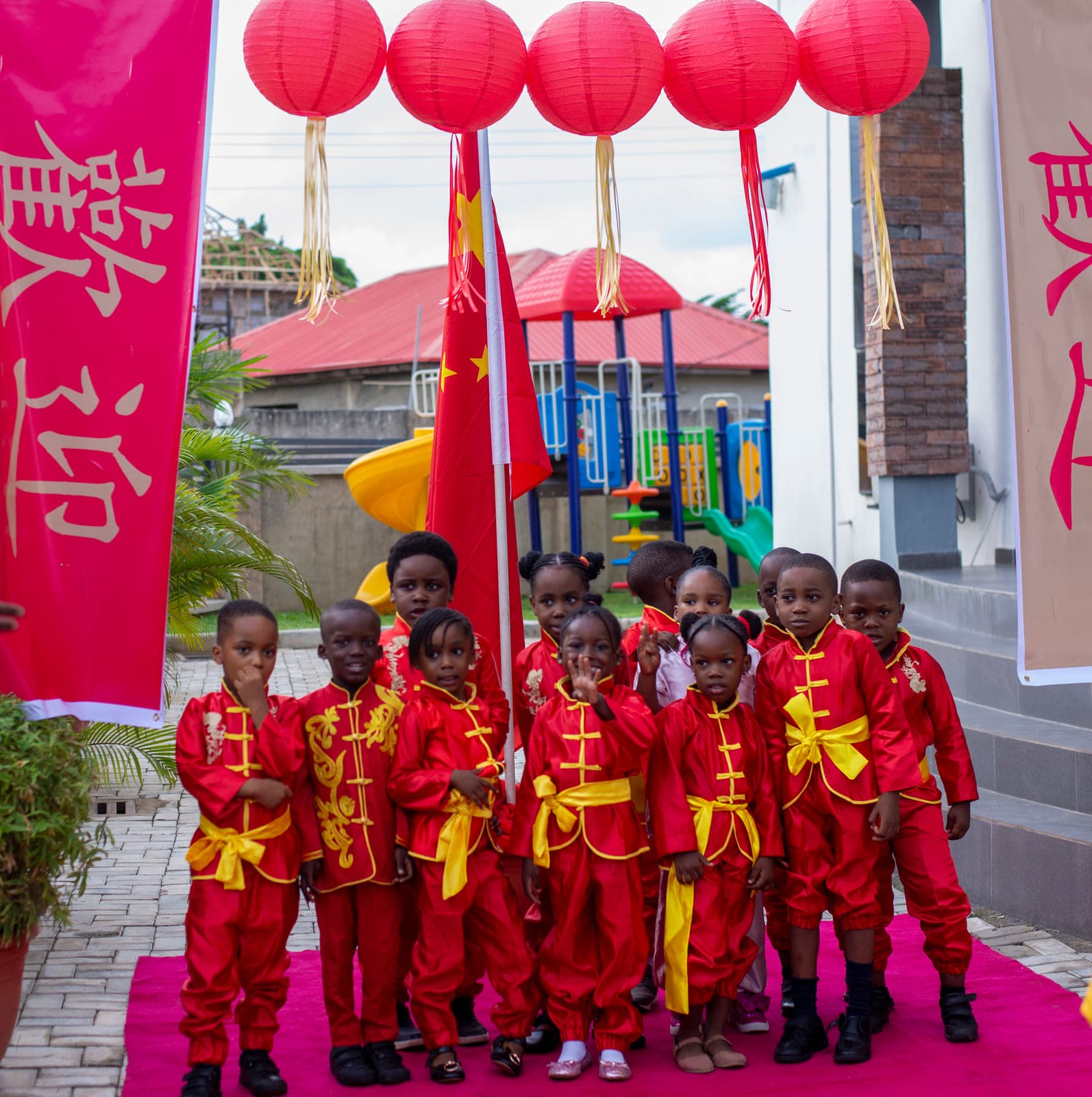 Pupils in red silk costume beneath the paper lanterns and welcome banners on Cultural Day