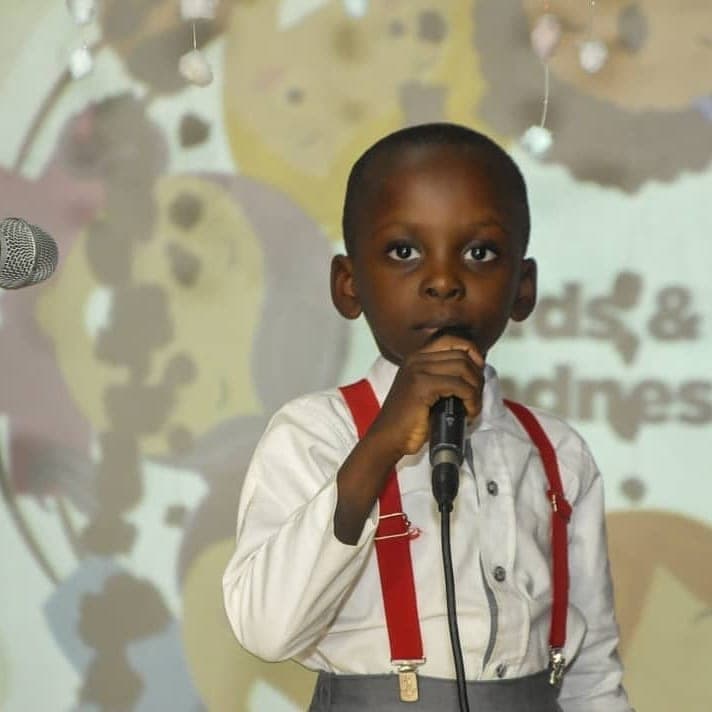 A young performer singing into the microphone on stage