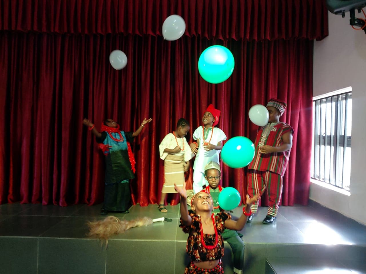 Balloons drifting above the cast during a scene in the school hall