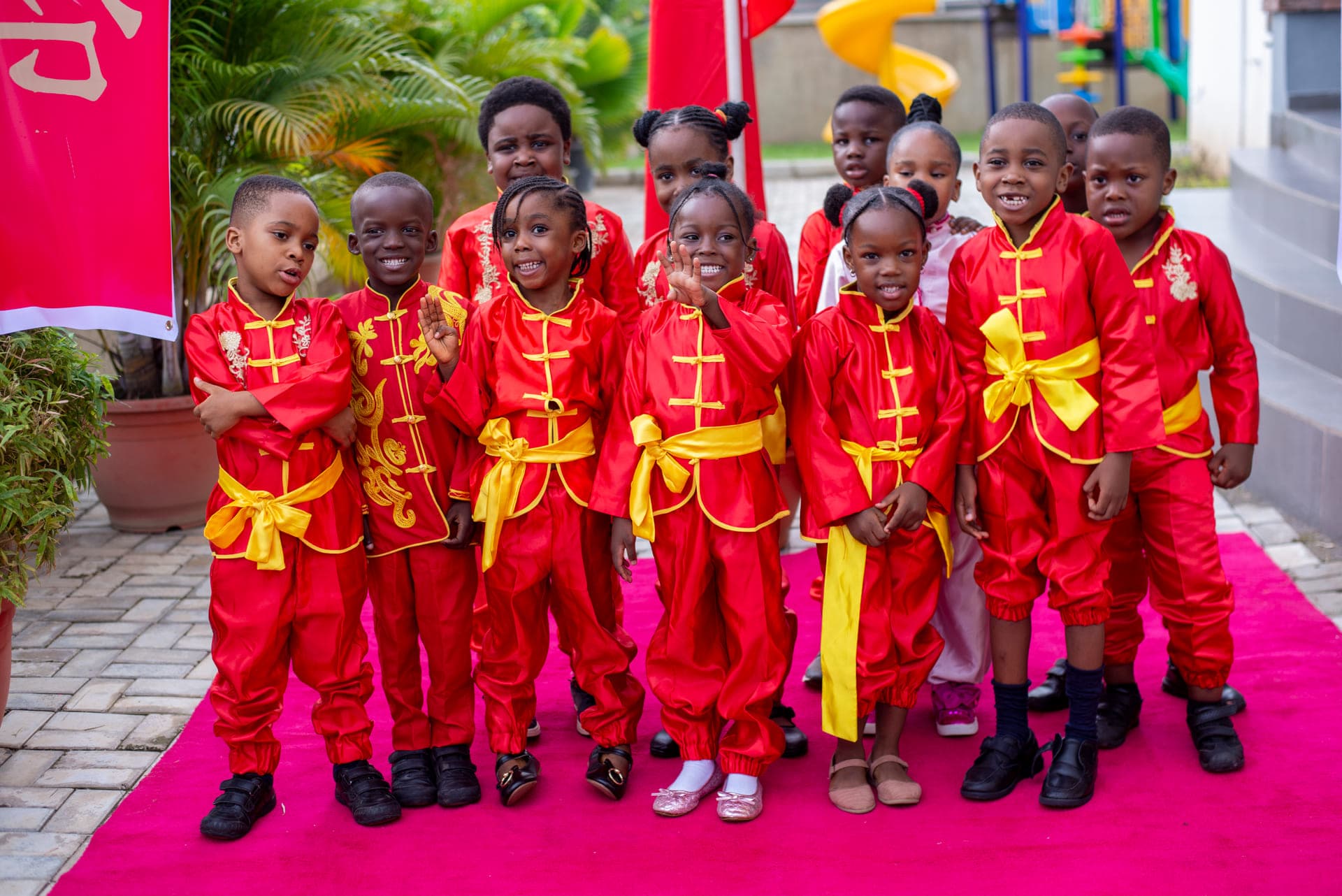 The cast in red silk costume with their teacher on the red carpet before Cultural Day