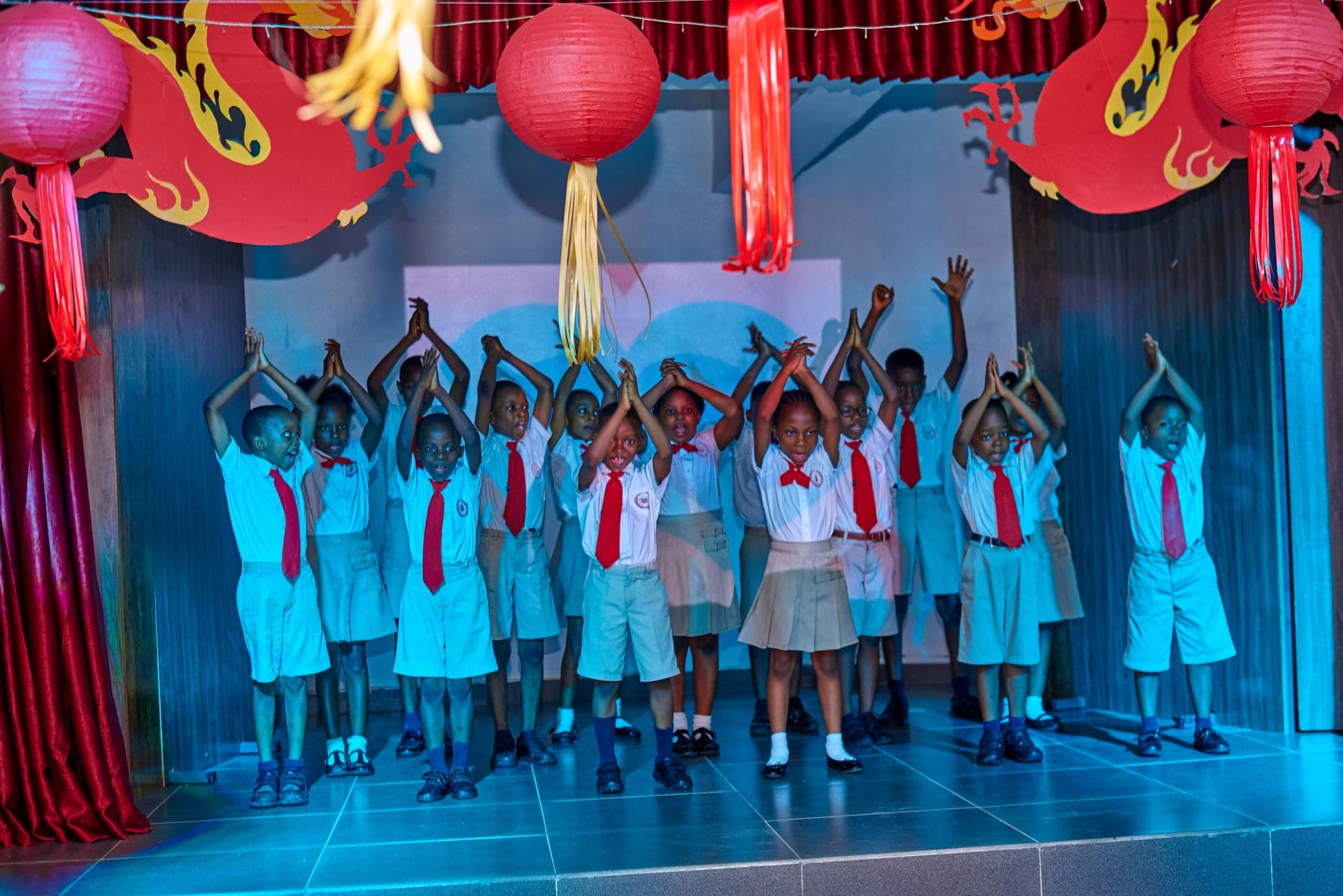A class dancing together on stage beneath red lanterns