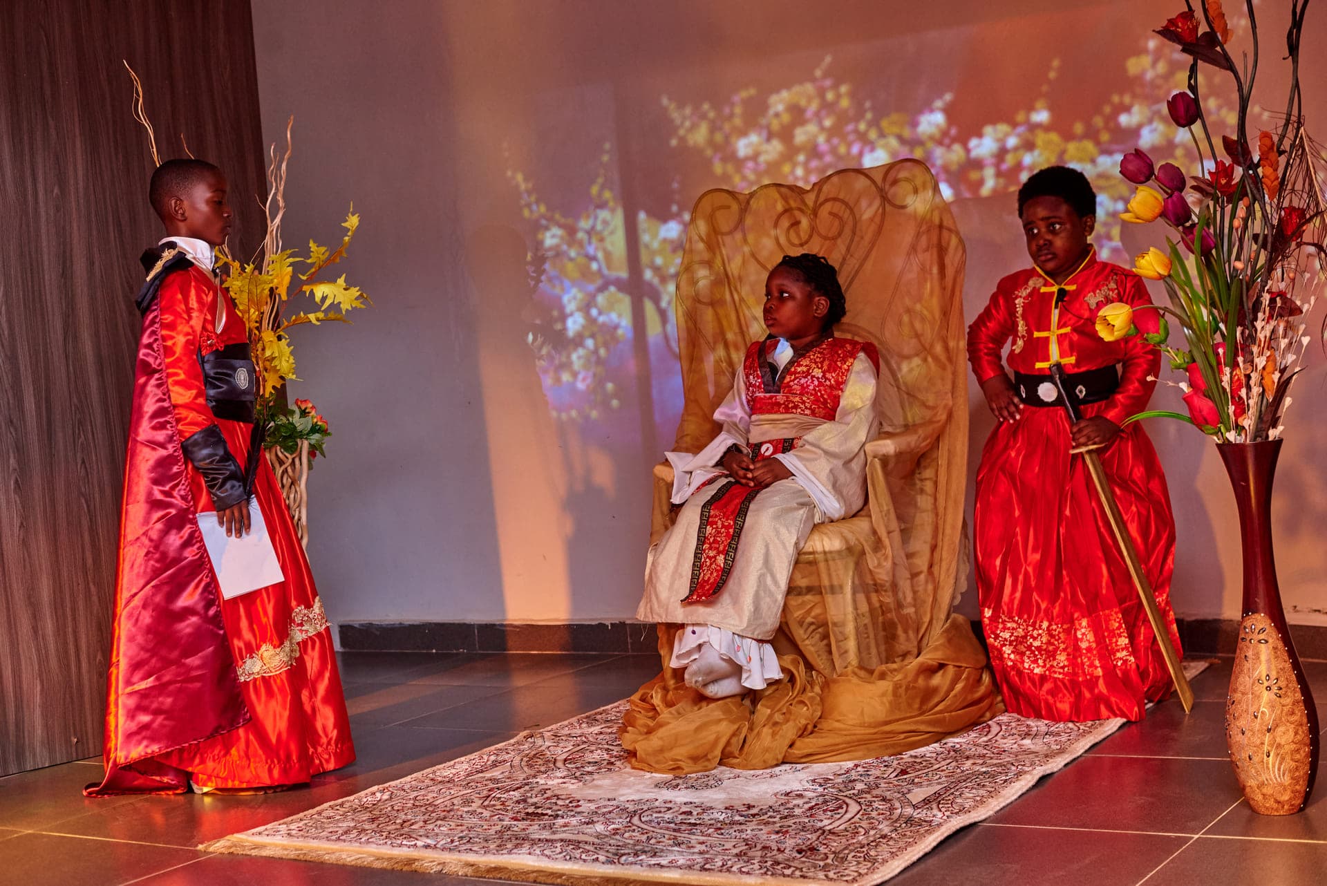 A pupil on the throne with her attendants in a scene from the Cultural Day play