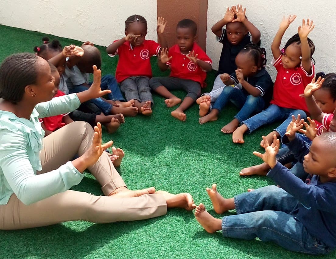 A teacher leading a clapping game with her class on the turf