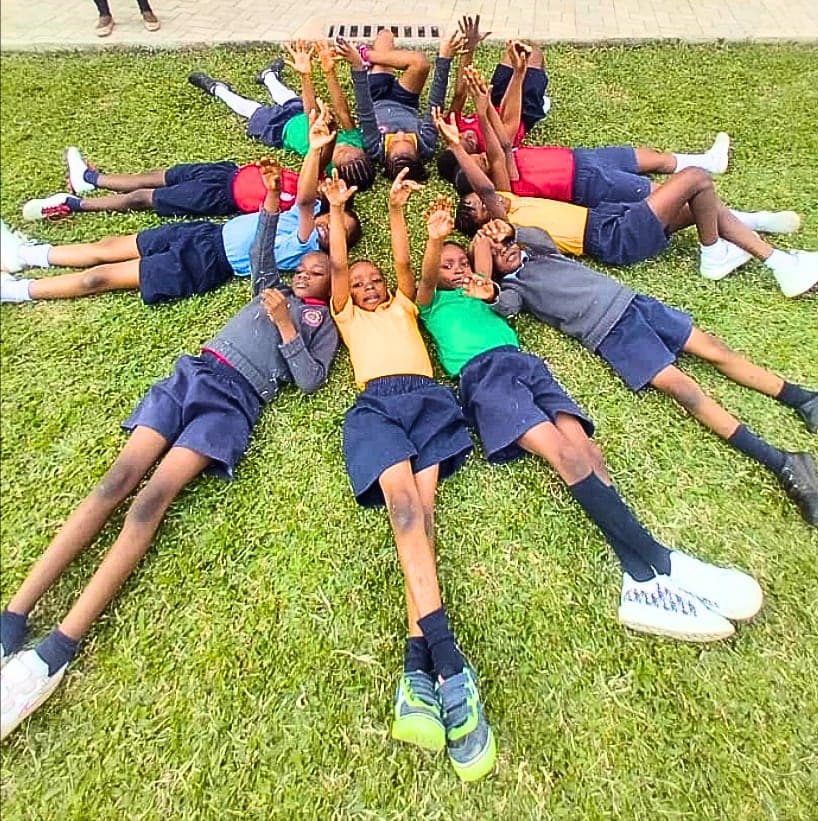 Pupils lying on the grass in a star formation, heads together
