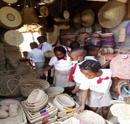 Pupils browsing woven baskets and hats at a local craft market