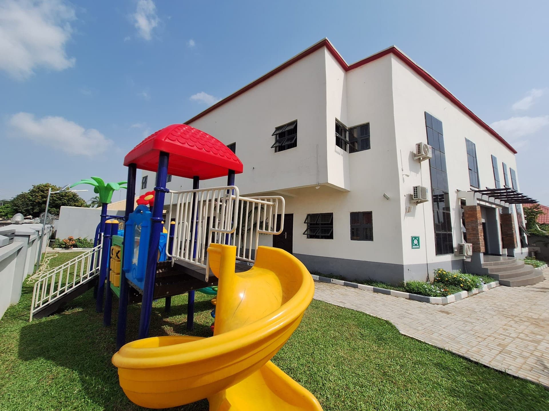 The outdoor playground with its climbing frame and spiral slide beside the main building