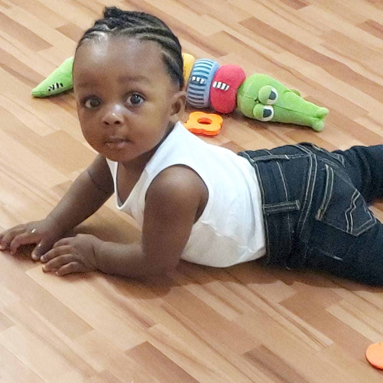 A toddler stretched out on the floor beside her toys
