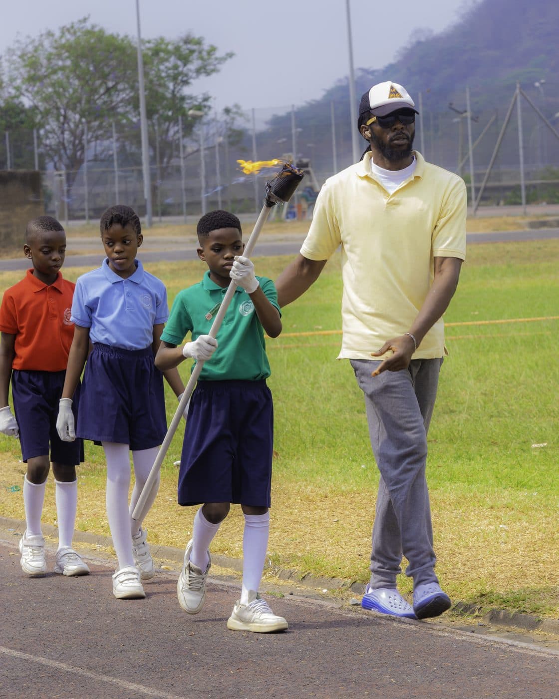 A coach working with pupils on the field at sports day