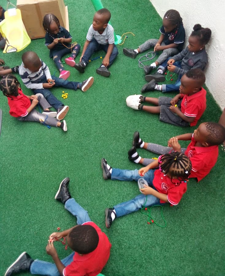 A class spread out on the turf with their reading books during an outdoor lesson
