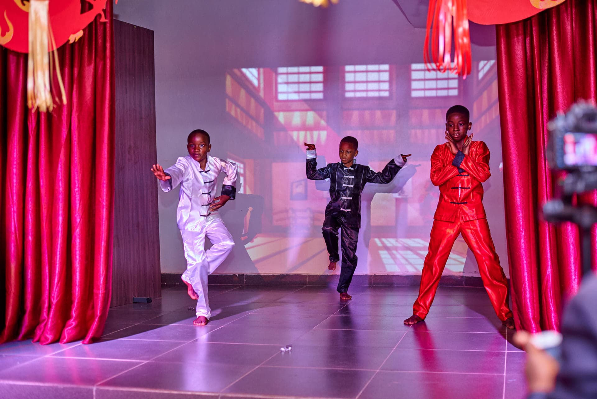Three pupils holding a martial arts stance on stage during Cultural Day