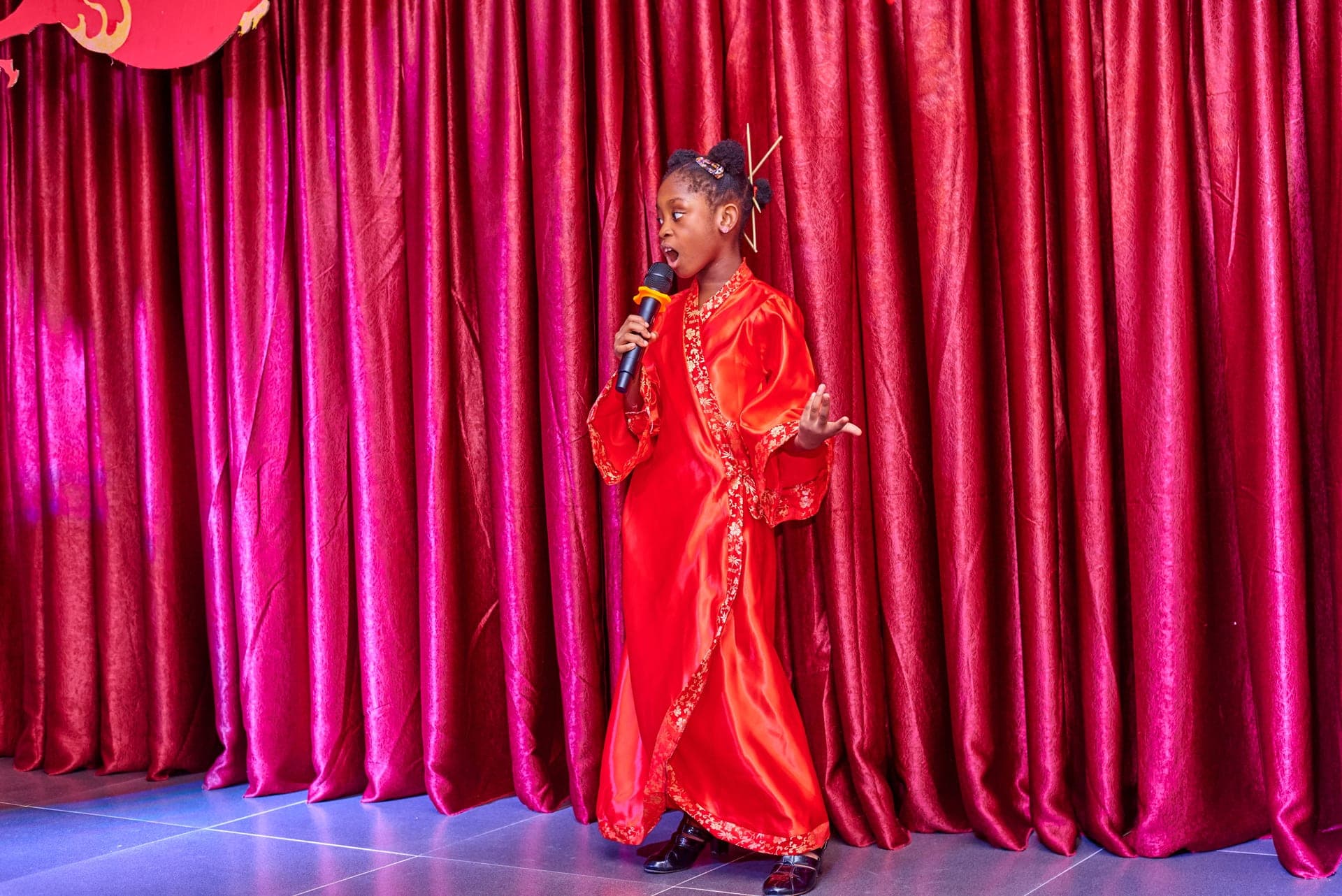 A pupil singing a solo in costume before the stage curtain