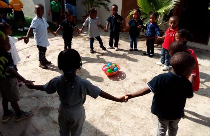 Children holding hands in a wide circle for a playground game
